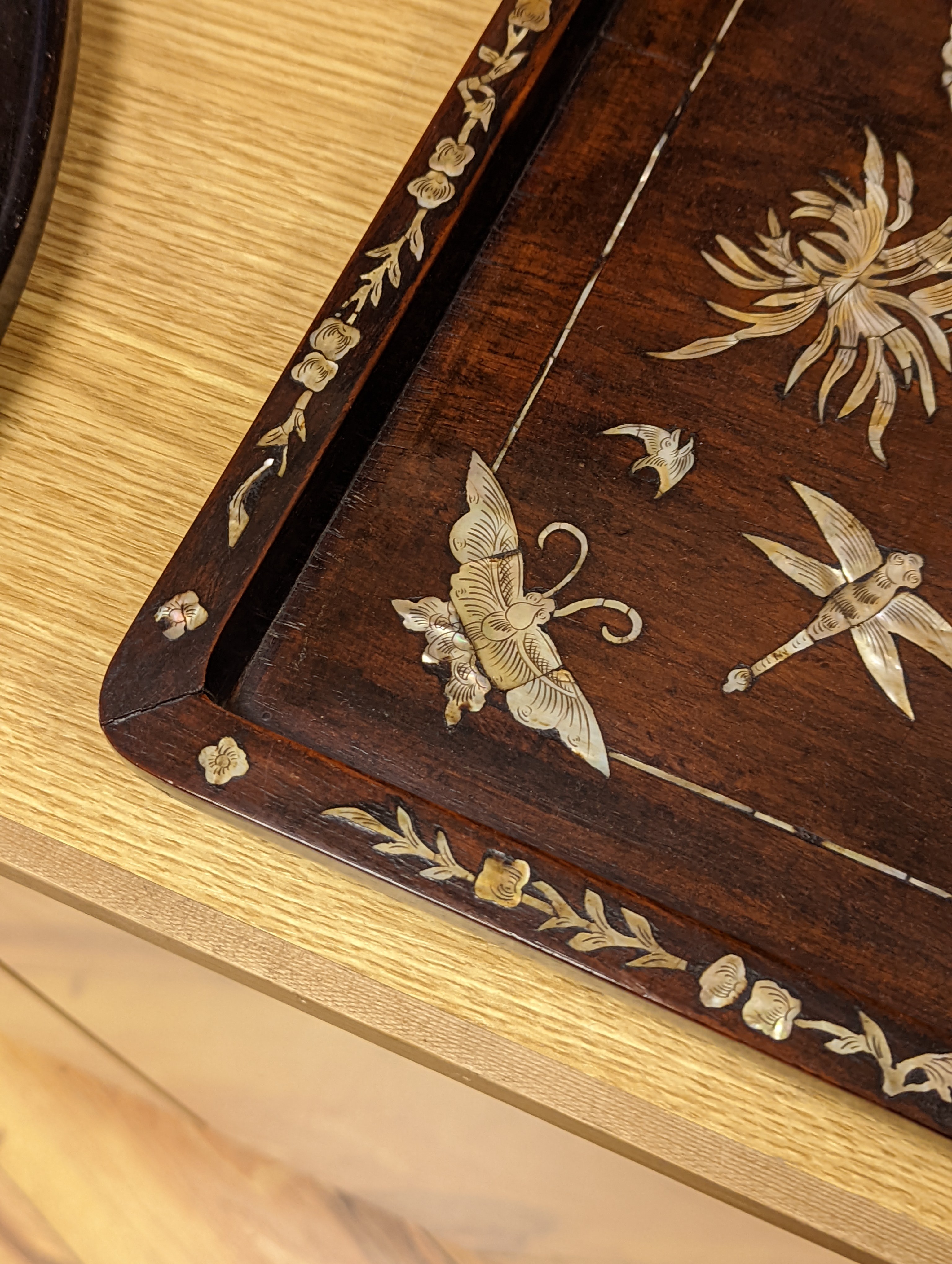Two Chinese mother of pearl inlaid hongmu trays, the rectangular example with birds and insects amid flowers and the smaller oval example with a pavilion in a landscape within floral sprays 55x34cm